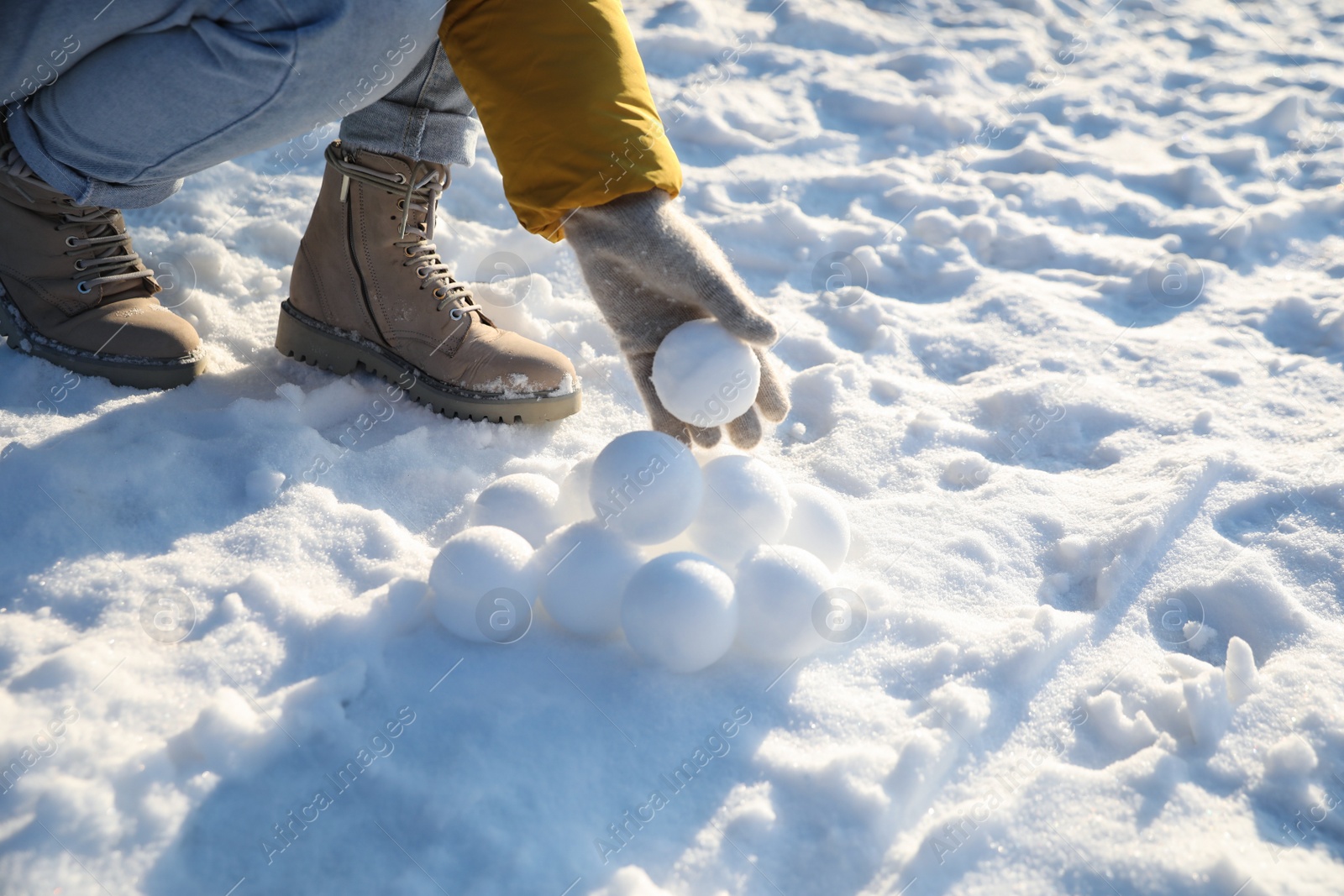 Photo of Woman rolling snowballs outdoors on winter day, closeup