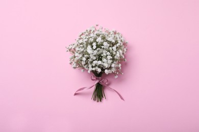 Bouquet of white gypsophila with ribbon on pink background, top view