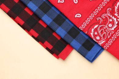 Photo of Folded bandanas with different patterns on beige background, flat lay