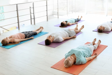 Photo of Group of people in sportswear practicing yoga indoors