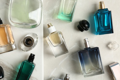 Photo of Perfume bottles on light background, flat lay