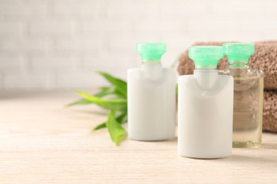 Photo of Mini bottles of cosmetic products on white wooden table, space for text