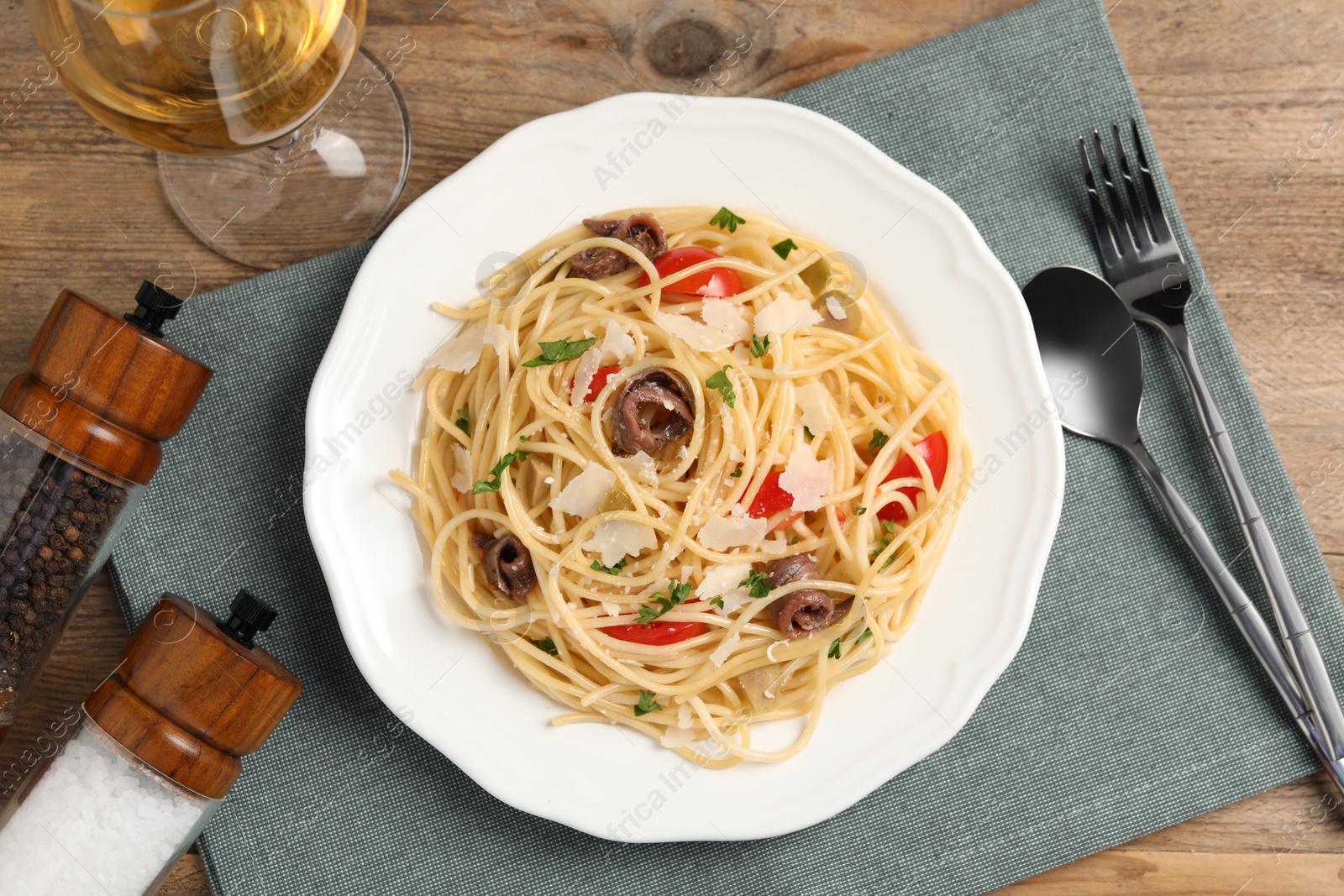 Photo of Delicious pasta with anchovies, tomatoes and parmesan cheese served on wooden table, flat lay