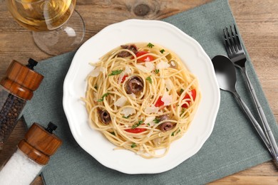 Delicious pasta with anchovies, tomatoes and parmesan cheese served on wooden table, flat lay