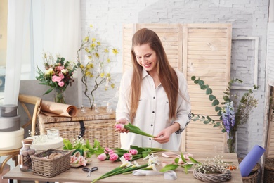 Photo of Female decorator creating beautiful bouquet at table