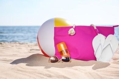 Bag and beach objects on sand near sea, space for text