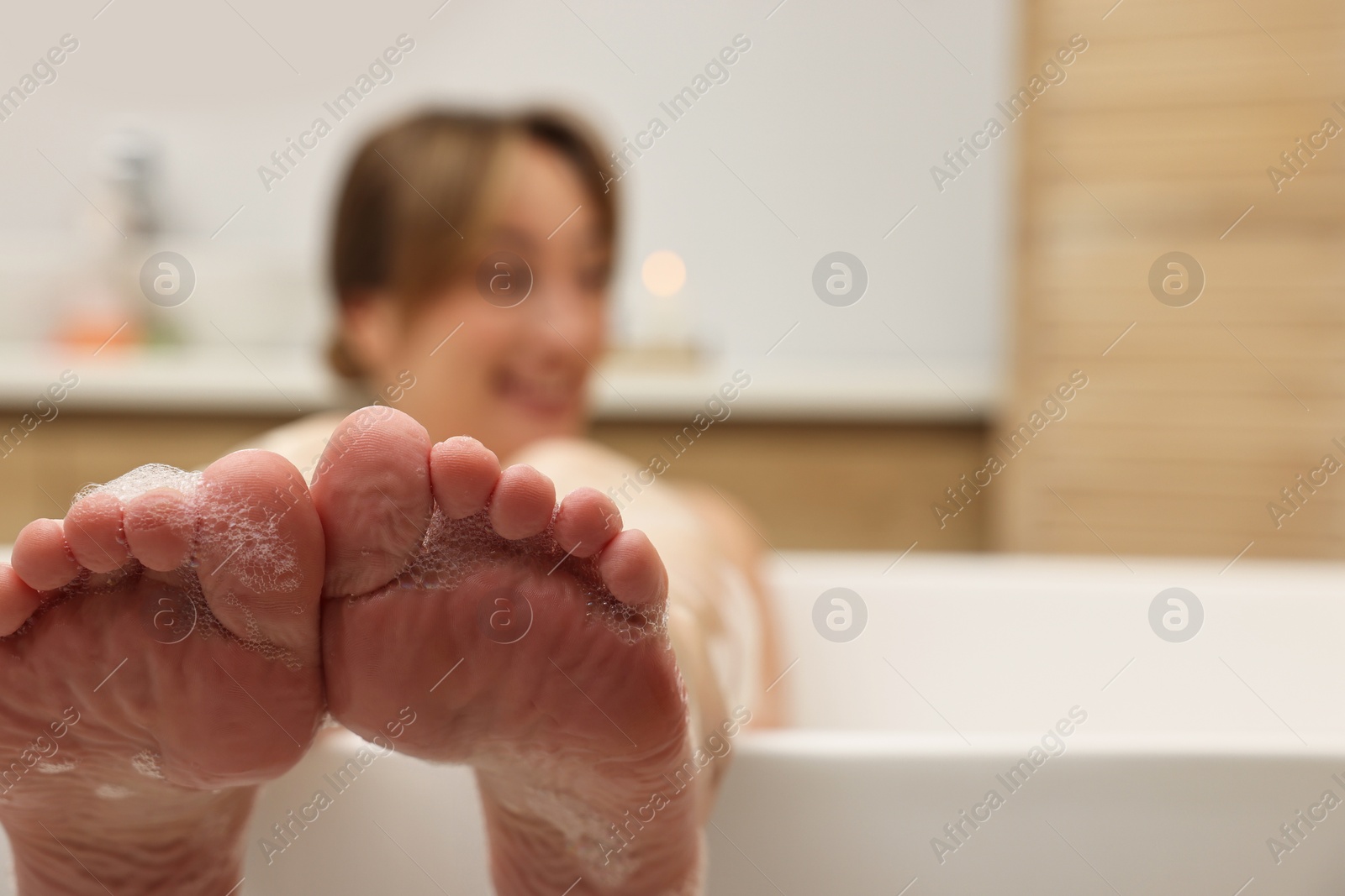 Photo of Woman taking bath in tub indoors, selective focus. Space for text