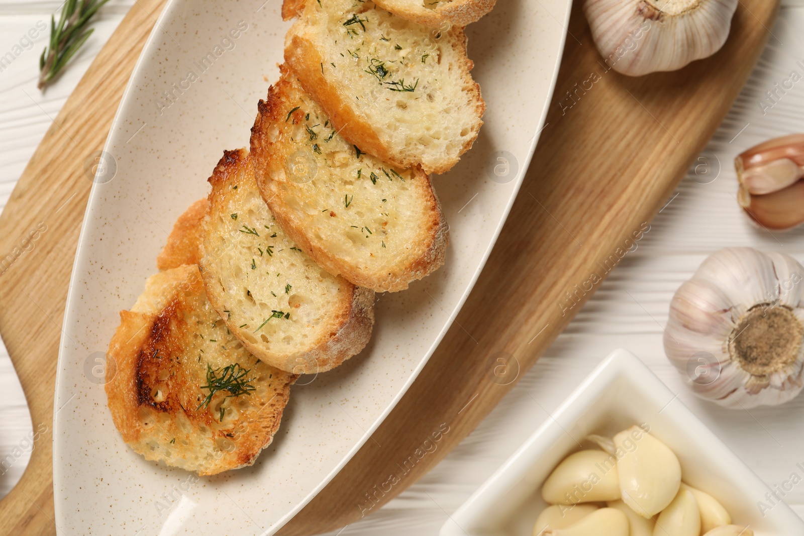 Photo of Tasty baguette with garlic and dill on white wooden table, flat lay