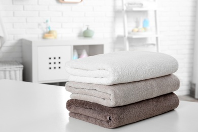 Photo of Stack of fresh towels on table in bathroom. Space for text