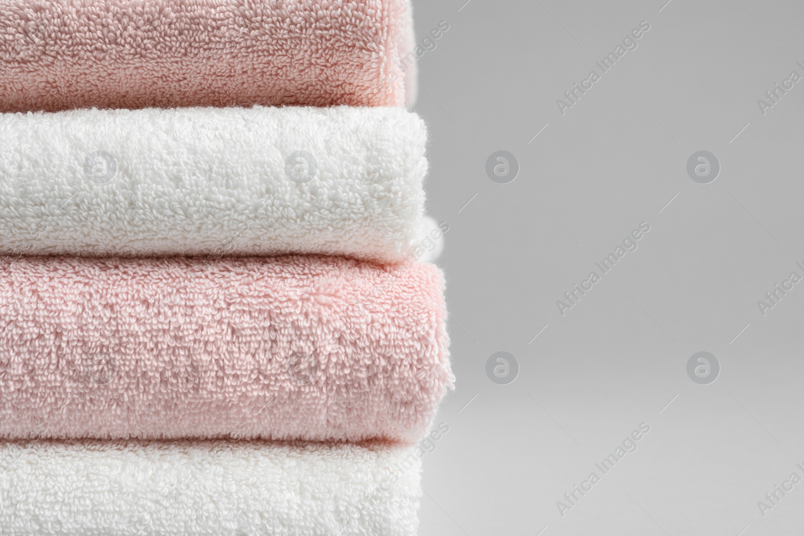 Photo of Stack of fresh towels on grey background, closeup. Space for text