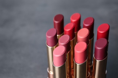 Photo of Set of bright lipsticks on grey background. Space for text