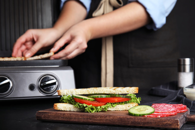 Tasty sandwich with tomato and cucumber on black table, closeup