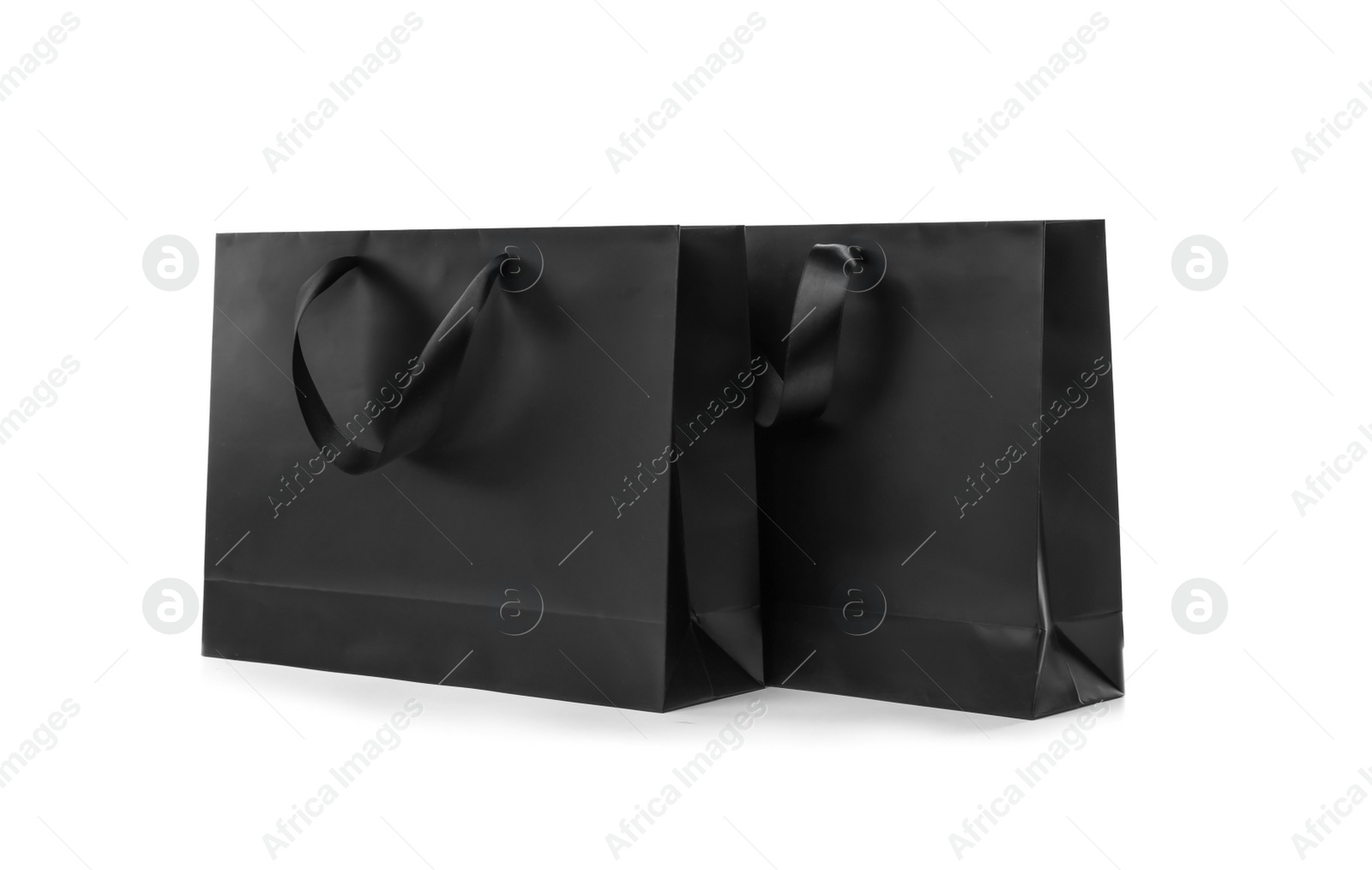 Photo of Paper shopping bags with ribbon handles on white background. Mockup for design