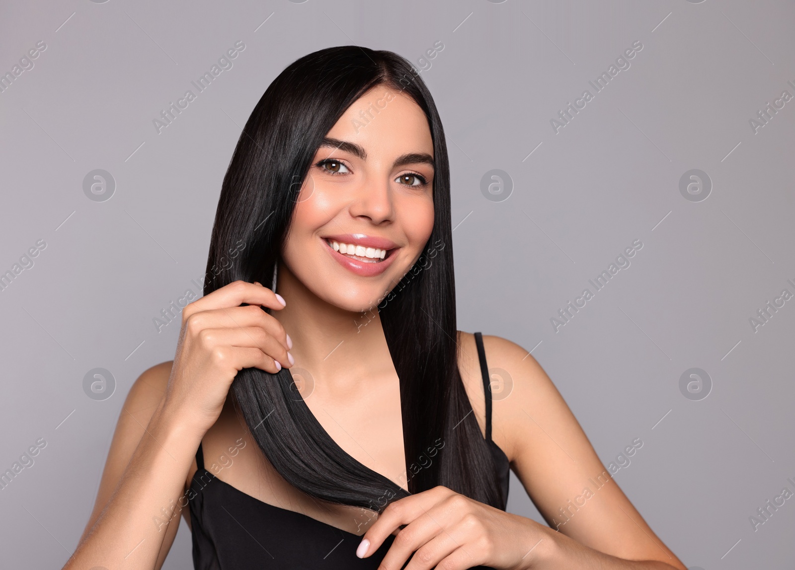 Photo of Portrait of beautiful young woman with healthy strong hair on light grey background