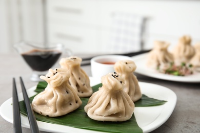 Photo of Plate with tasty baozi dumplings and chopsticks on table