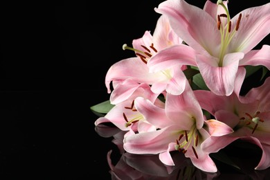 Photo of Beautiful pink lily flowers on black background. Space for text