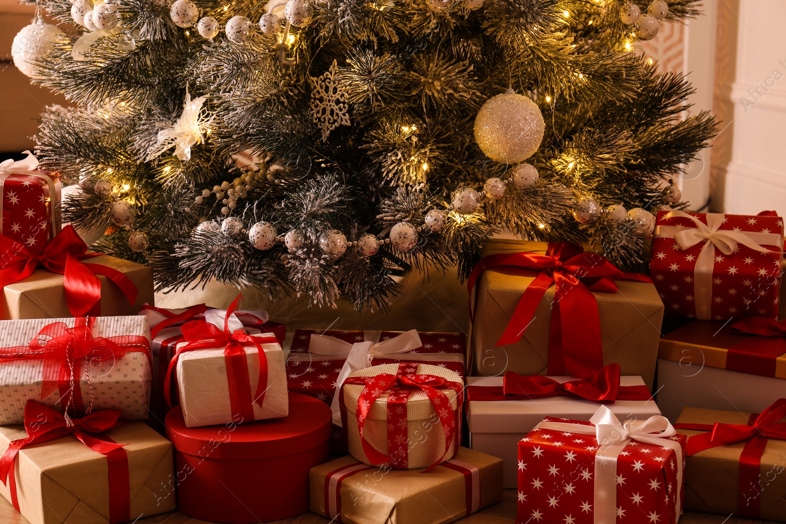 Photo of Pile of gift boxes near beautiful Christmas tree indoors