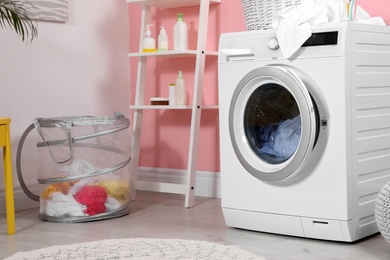 Modern washing machine near wall in laundry room