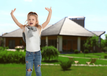 Image of Happy little girl jumping near house, space for text. School holidays
