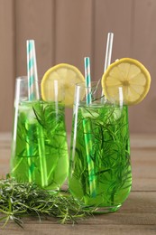 Glasses of refreshing tarragon drink with lemon slices on wooden table