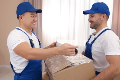 Workers wrapping box in stretch film indoors