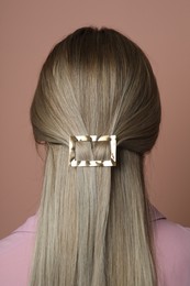 Photo of Young woman with beautiful gold hair clip pin on pink background, back view