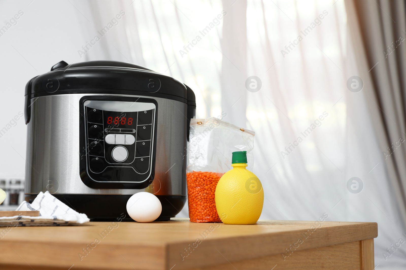 Photo of New modern multi cooker and products on table in kitchen. Space for text