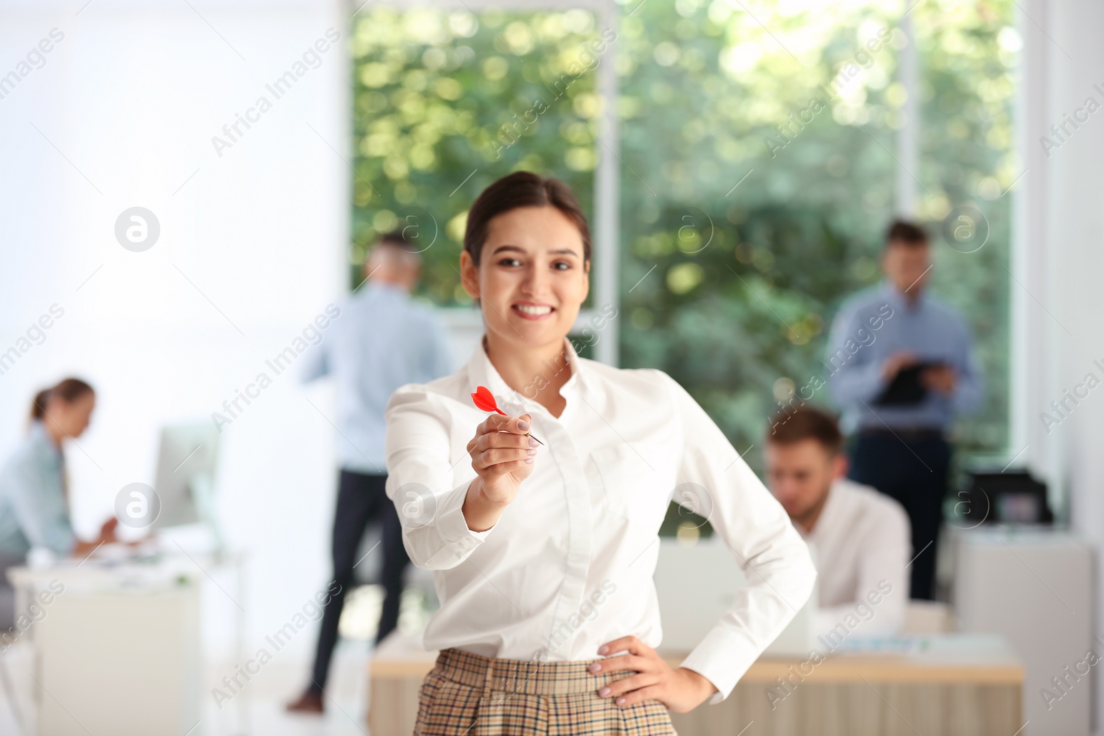 Photo of Happy young businesswoman with dart in office