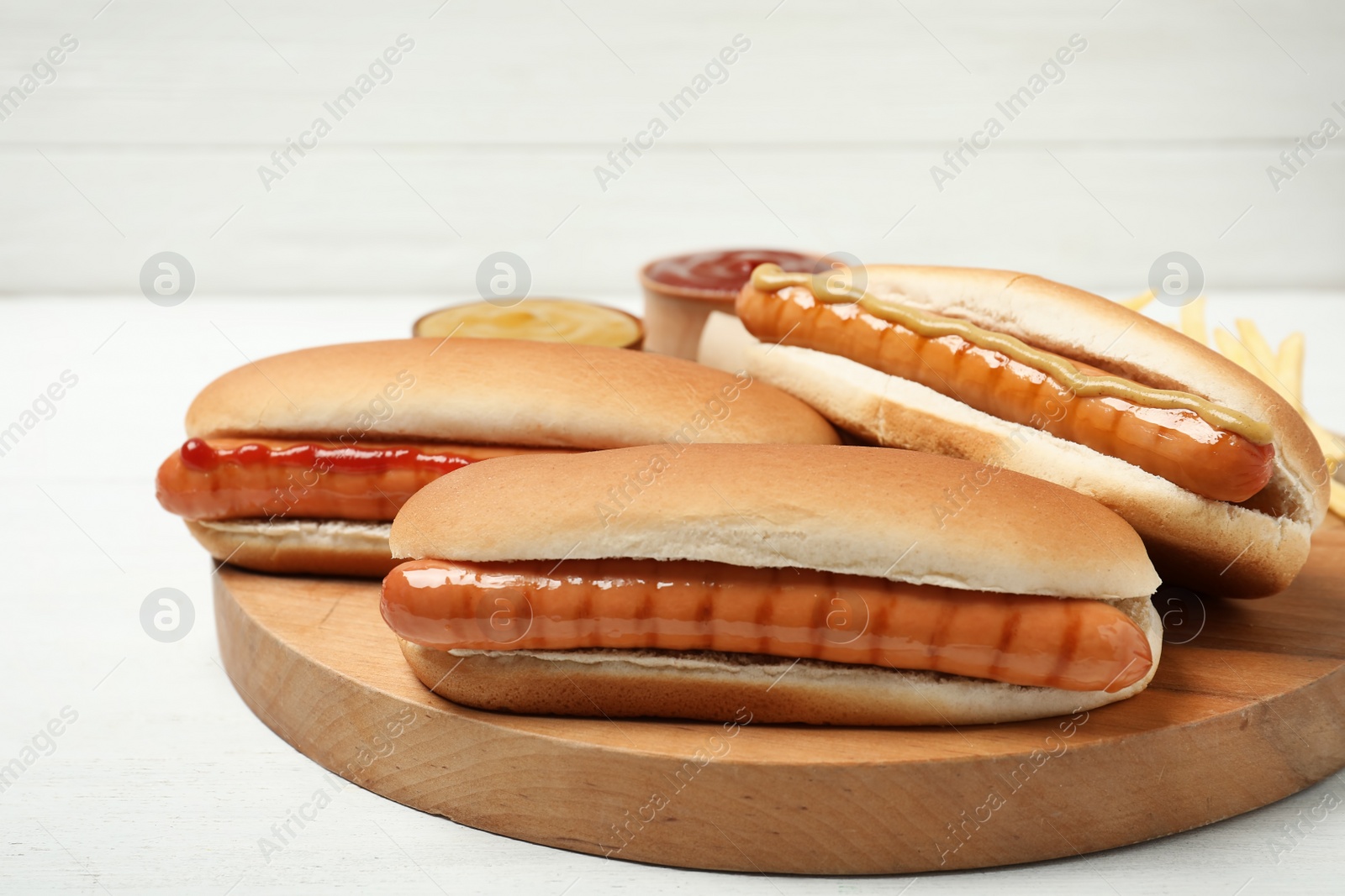 Photo of Tasty hot dogs on wooden board, closeup