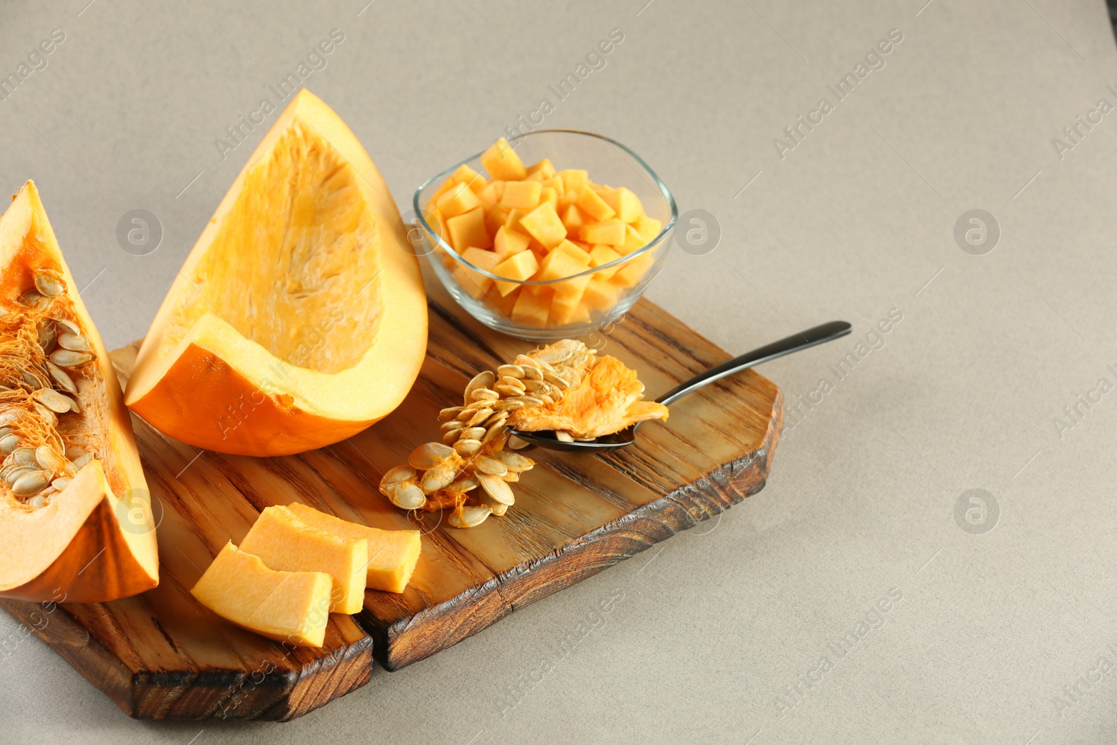 Photo of Cut fresh ripe pumpkin on grey background, space for text