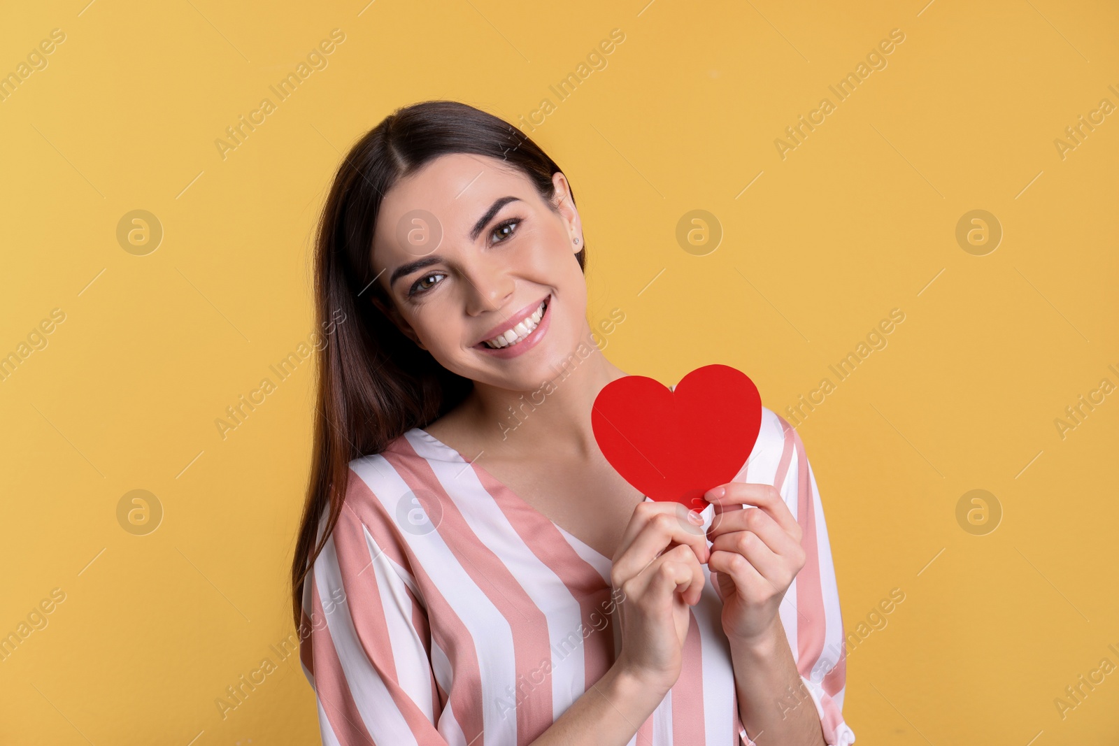 Photo of Portrait of young woman with paper heart on color background