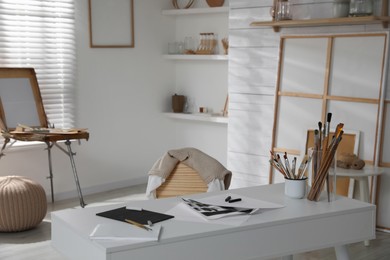 Photo of Modern studio interior with artist's workplace and wooden easel