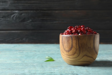 Wooden bowl with cranberries on table, space for text. Dried fruit as healthy snack