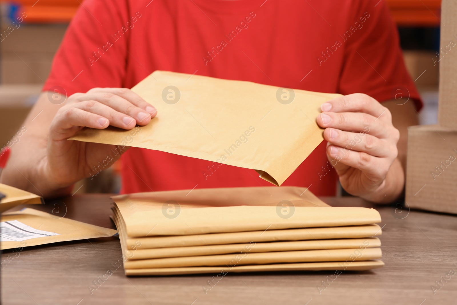 Photo of Post office worker with adhesive paper bags at counter indoors, closeup