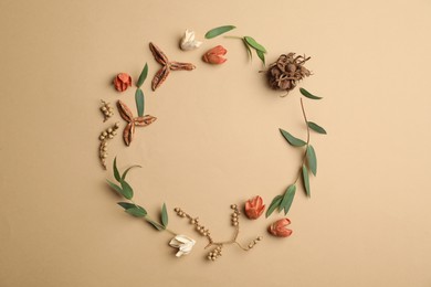 Photo of Dried flowers, leaves and seeds arranged in shape of wreath on beige background, flat lay with space for text. Autumnal aesthetic