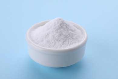Photo of Bowl of sweet powdered fructose on light blue background