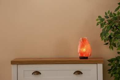 Photo of Himalayan salt lamp on cabinet against light wall