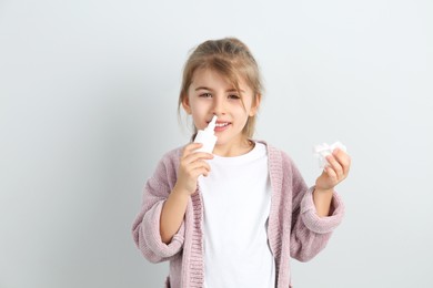 Photo of Sick little girl using nasal spray on white background