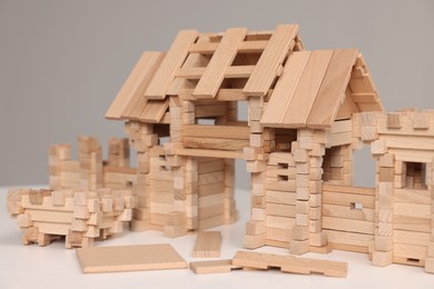 Wooden entry gate and building blocks on white table against grey background, closeup. Children's toy