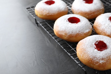 Photo of Hanukkah doughnuts with jelly and sugar powder on grey background, closeup. Space for text