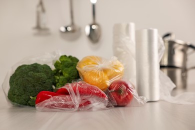 Plastic bags with fresh products on white table