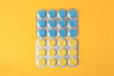 Photo of Blisters with cough drops on yellow background, flat lay