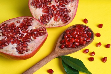 Photo of Composition with ripe pomegranates and wooden spoon on color background