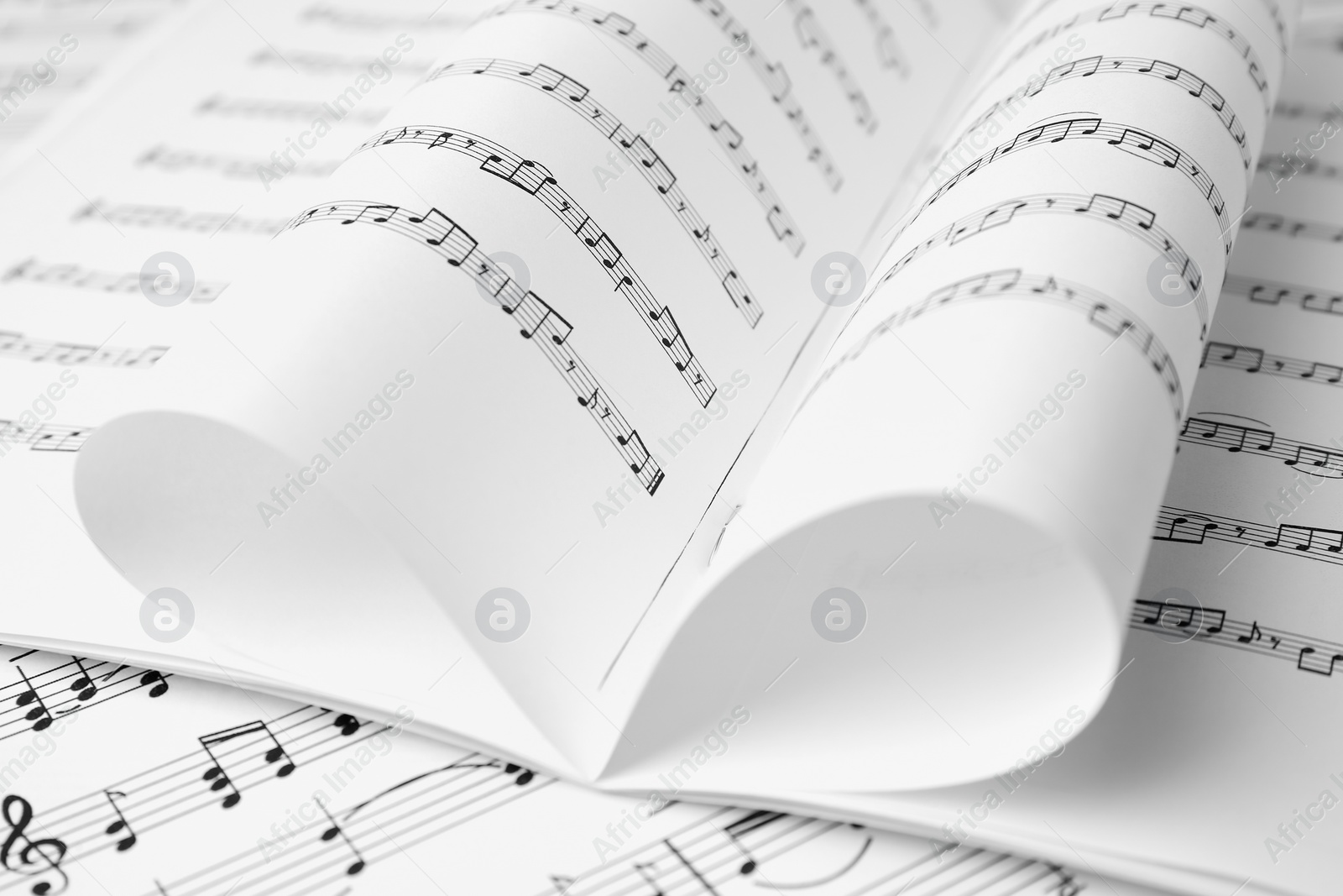 Photo of Sheets of paper with music notes as background, closeup