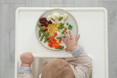 Photo of Cute little baby eating healthy food, top view