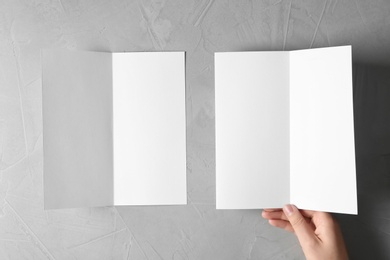 Woman with blank brochures on grey background, top view. Mockup for design