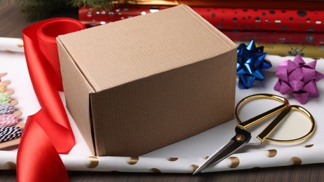 Photo of Box, wrapping paper and scissors on wooden table, closeup