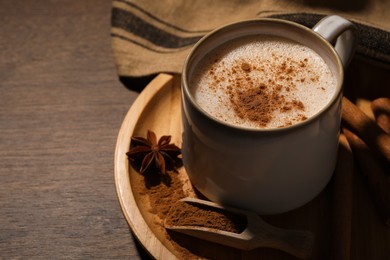 Cup of delicious eggnog with spices on wooden table. Space for text