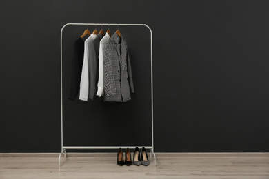 Photo of Rack with stylish clothes near black wall