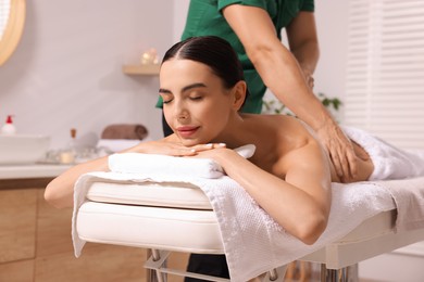 Photo of Woman receiving professional back massage on couch in spa salon
